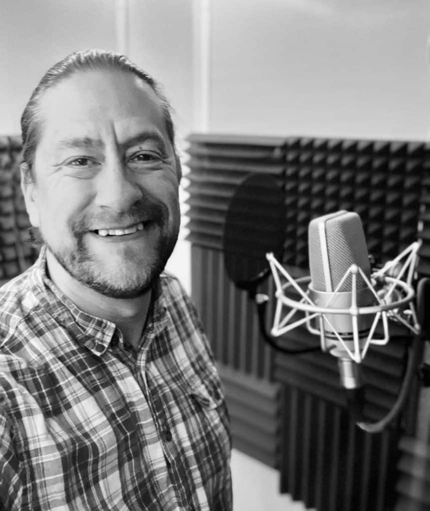 Mark Thomas, a British Voiceover Artist in a studio in front of a microphone